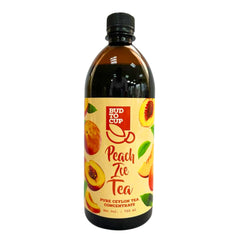 A 750 ml bottle of Bud to Cup Peach Tea Concentrate, featuring a black cap and a cream-colored label decorated with illustrations of peaches and green leaves, set against a plain white background.