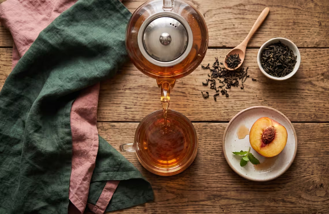 Glass teapot pouring Ceylon black tea with steam rising