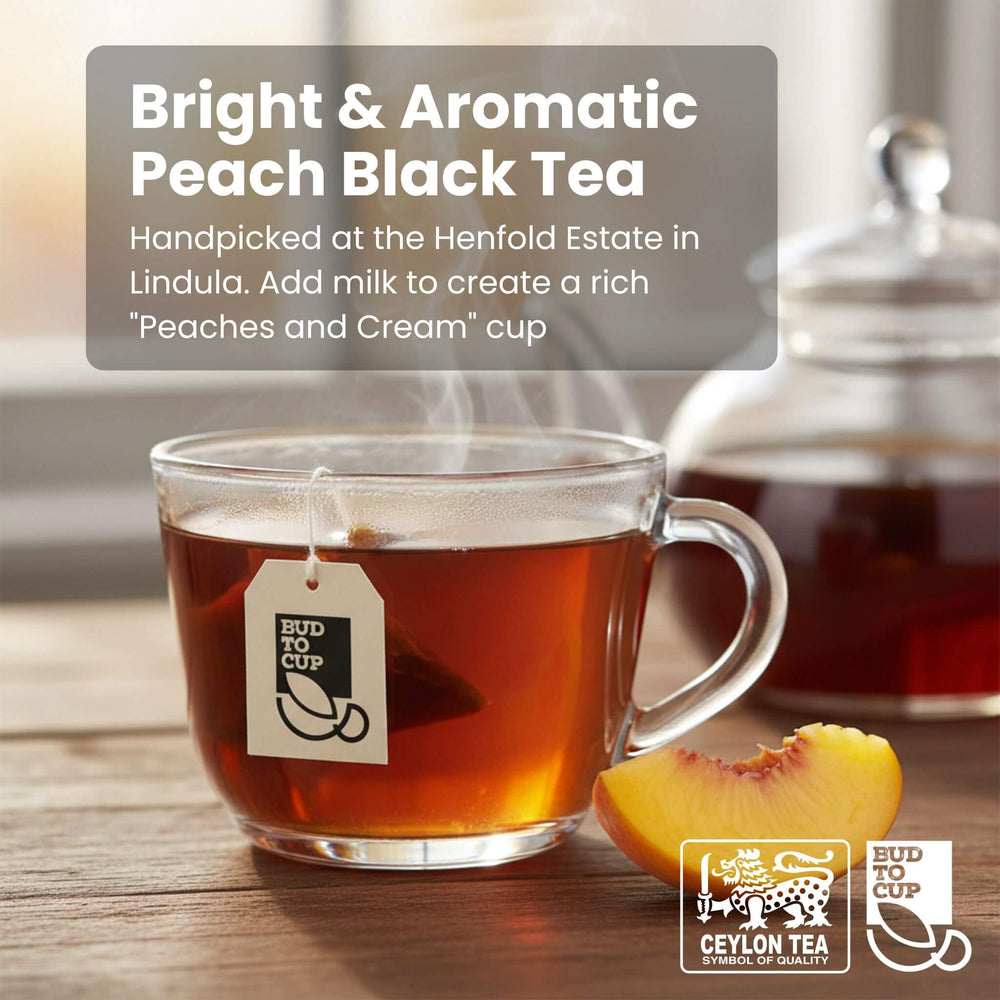 Glass of peach black tea with a teabag, peach slice, and teapot on a wooden surface.